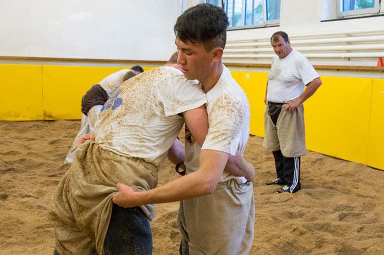Rohoullah aus Afghanistan beim Schwingen. Im Hintergrund beobachtet Schwingerkönig Ernst Schläpfer das Training. | Peter Leutert